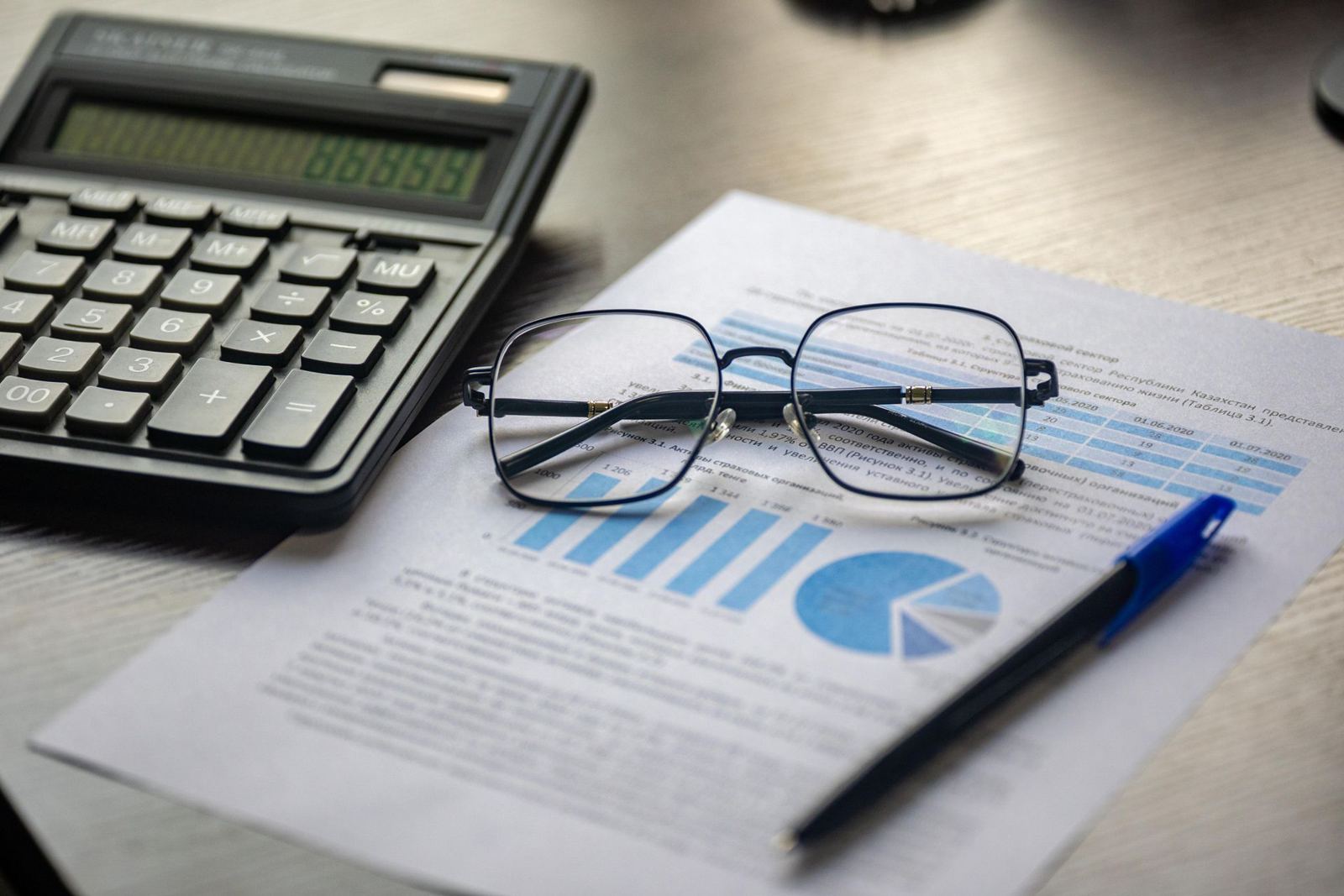 Financial report with a calculator, pen and reading glasses